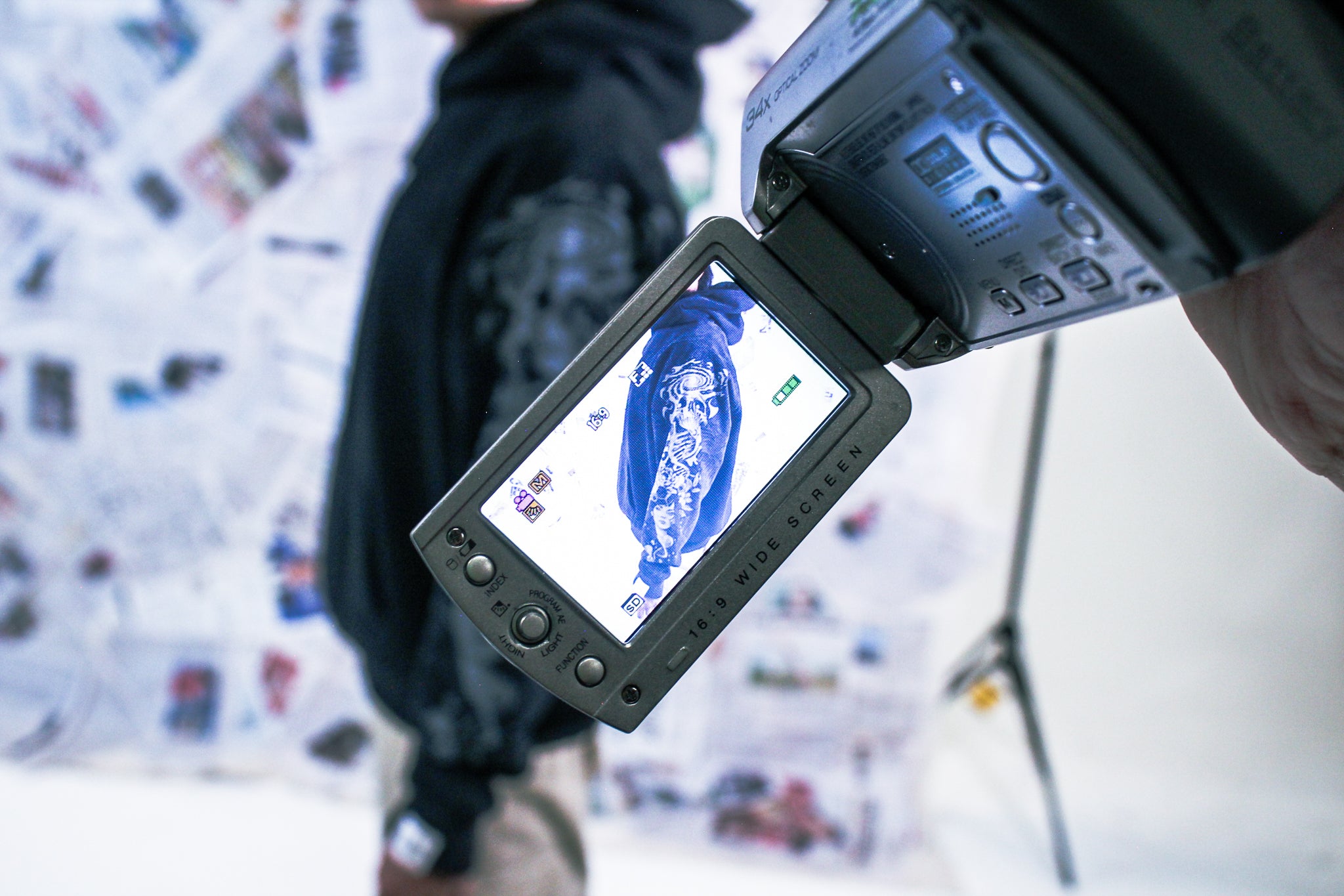 Camera with screen displaying a person with a newspaper background
